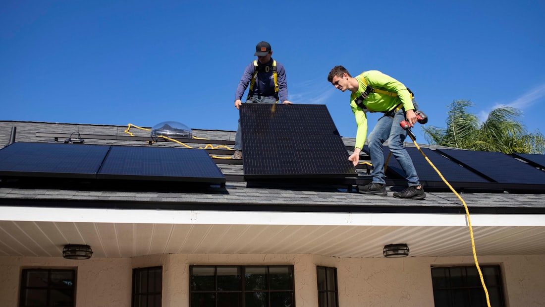 Deux poseurs installant des panneaux photovoltaïques sur une toiture